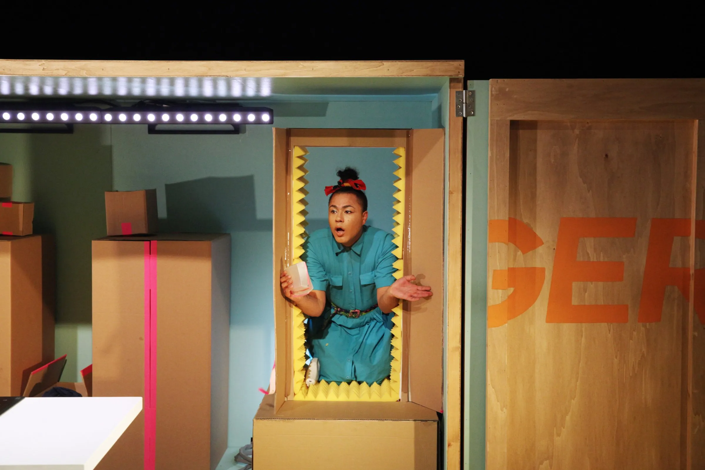 Travis Alabanza in a cardboard box doorway on the set