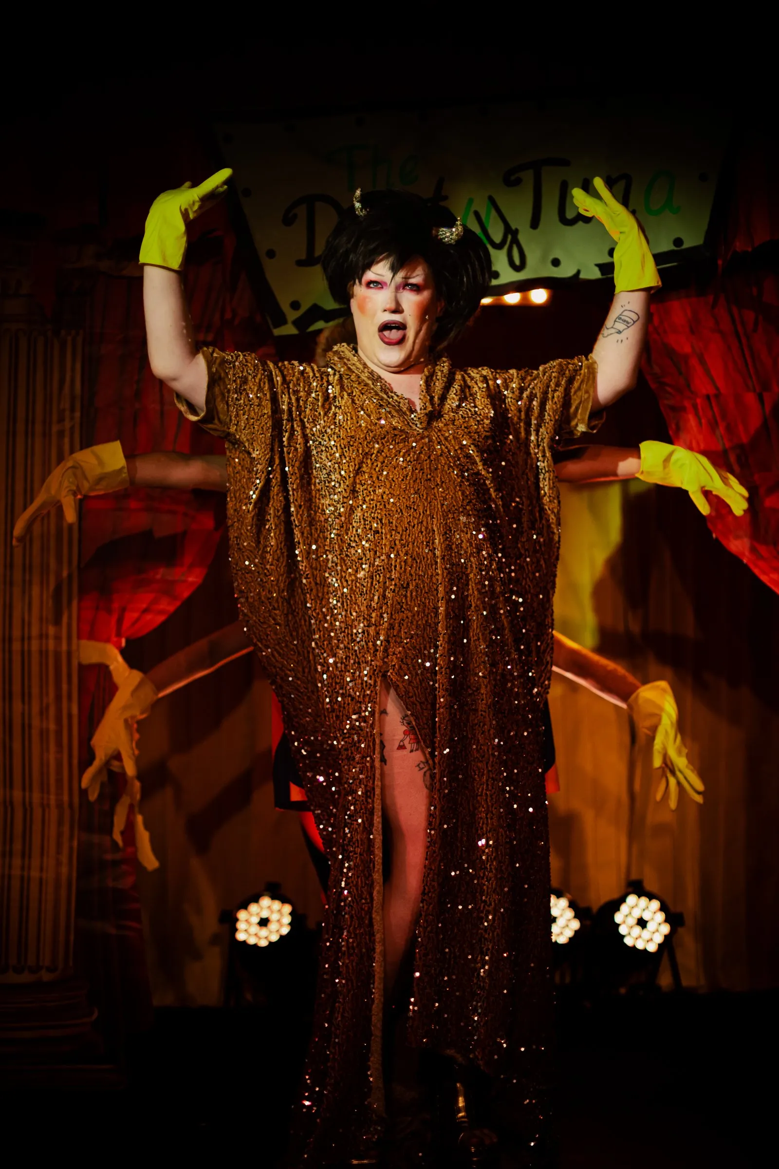 Ms Sharon Le Grand in gold sequins with gloved hands behind