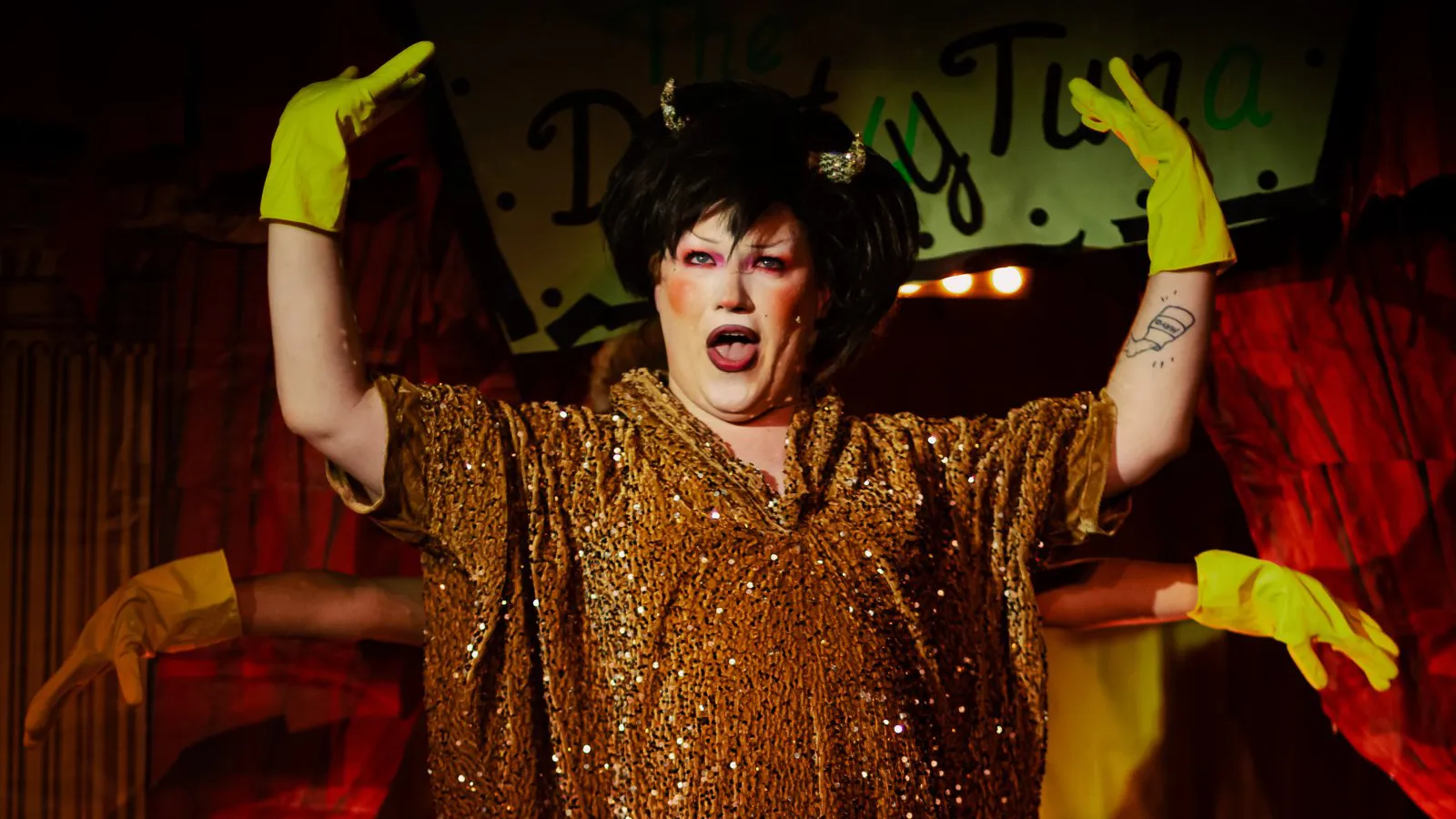 Ms Sharon Le Grand in gold sequins with gloved hands behind