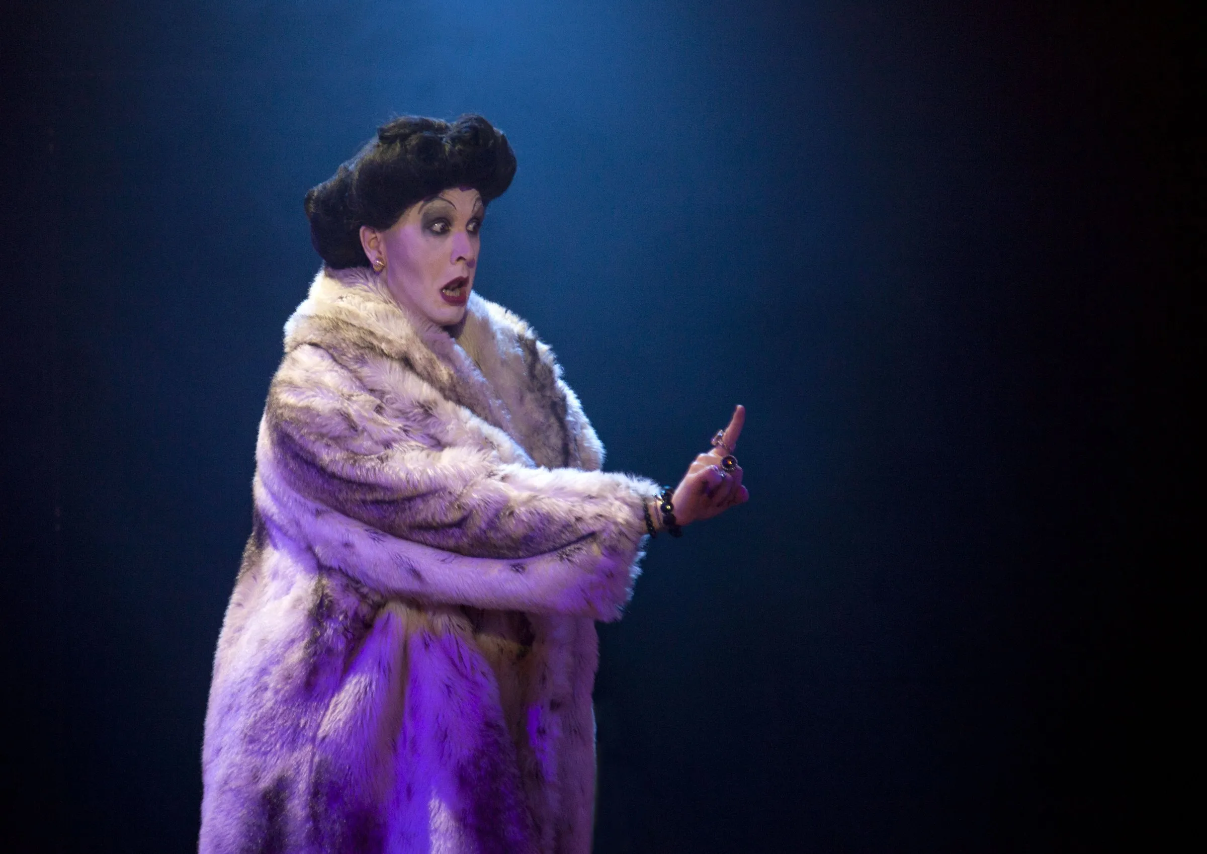 Peter Clements as Frau Welt in a fur coat raising a finger