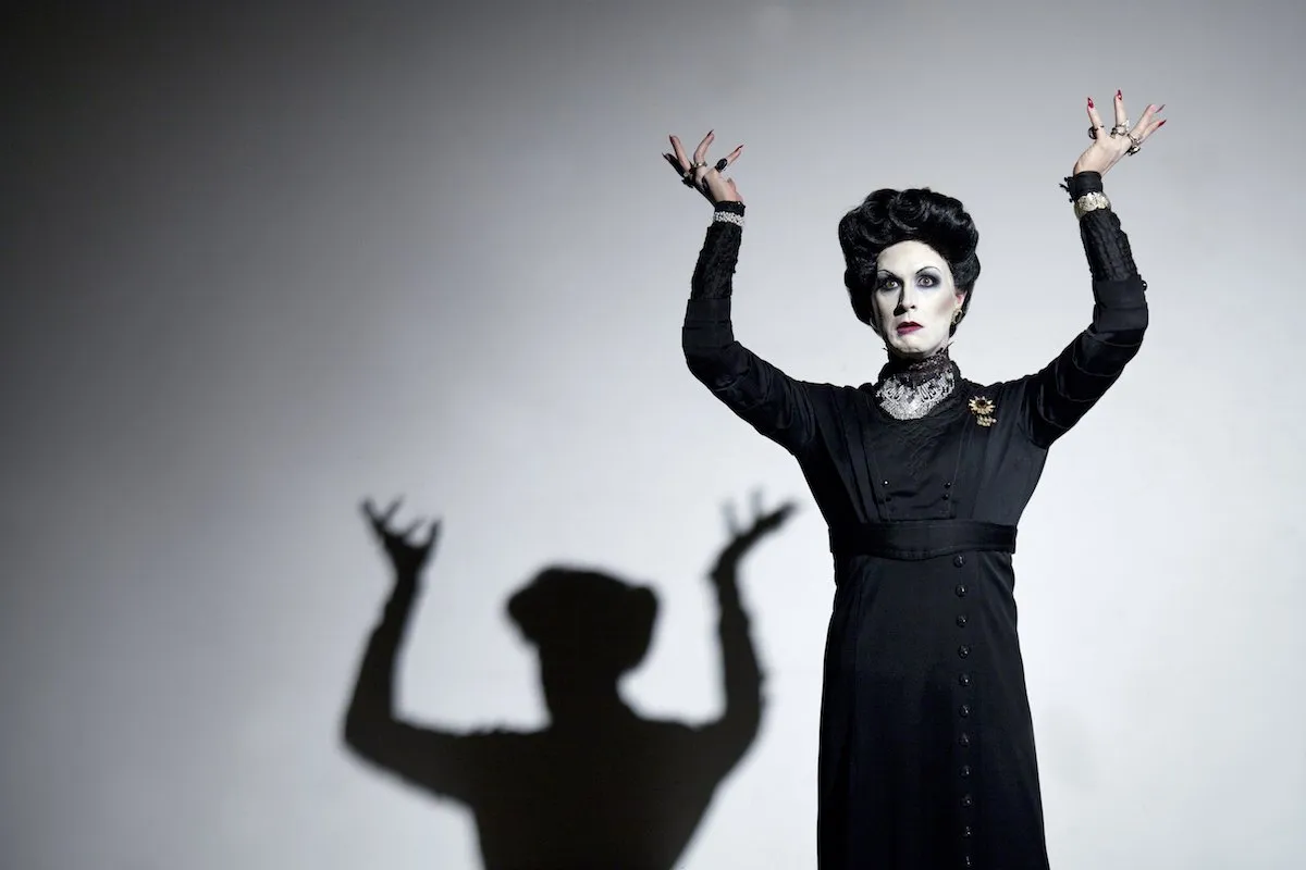 Peter Clements as Frau Welt with arms raised and her shadow behind