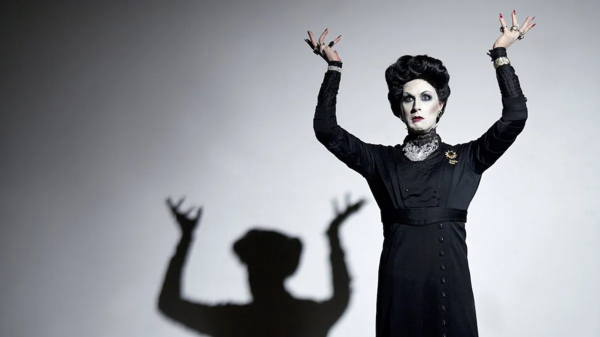 Peter Clements as Frau Welt with arms raised and her shadow behind